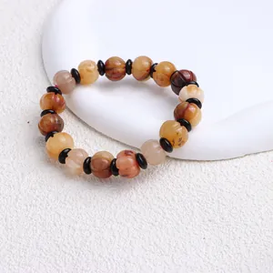 Nahaufnahme eines Armbands aus natürlicher Goldseidenjade mit geschnitzten Kürbisperlen.