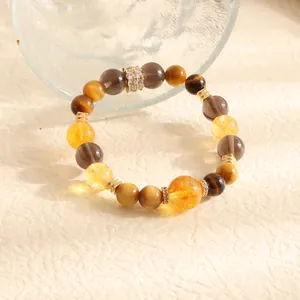 Detail showing mixed natural tiger eye and citrine beaded bracelet on textured background