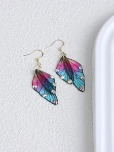 Close-up detail of butterfly wing earrings with gradient colors and rhinestone accents.