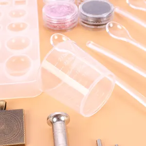 Close-up of measuring cup and silicone mold from a 107-piece DIY resin jewelry kit