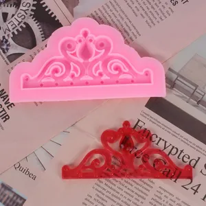 Dettaglio dello stampo in silicone per tiara con colata in resina rossa finita su giornale.