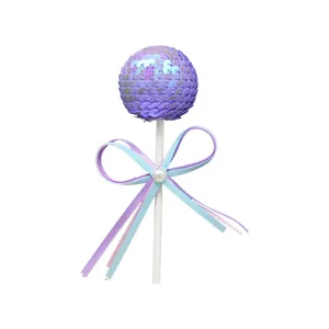 Sparkling purple sequin ball cake topper featuring a pastel ribbon bow and pearl decoration