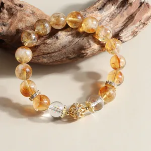 Detailed close-up of natural yellow crystal and gold-tone beads on a wooden prop.