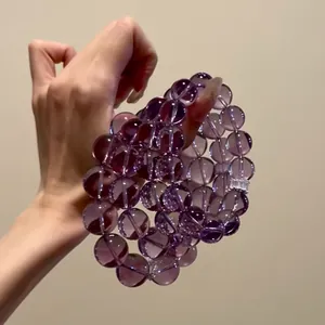 Close-up of natural purple amethyst bead bracelets held in hand.