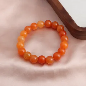 Detaillierte Nahaufnahme eines leuchtend orangefarbenen Sonnenstein-Armbands auf Satin