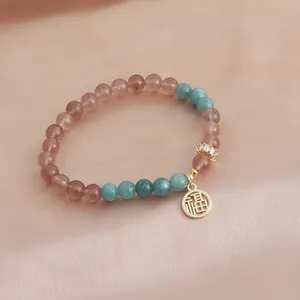 Detailed view of strawberry quartz crystal bracelet with gold Fu character charm