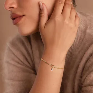Gold-plated initial K bracelet with snake chain and pavé letter pendant on model