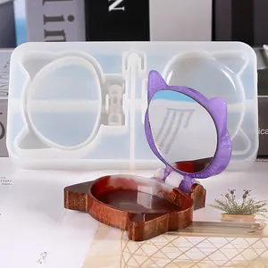 Cat-shaped silicone mold with finished purple resin compact mirror on a magazine
