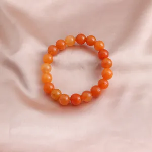 Detailaufnahme eines natürlichen orangefarbenen Sonnenstein-Perlenarmbands auf Seide