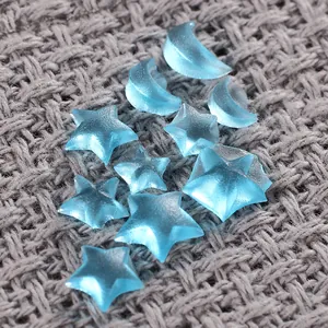 Detailed view of light blue translucent star and moon resin shapes on a knitted surface.