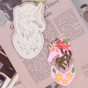 Detailed view of unicorn silicone mold and finished clay piece on decorative paper.