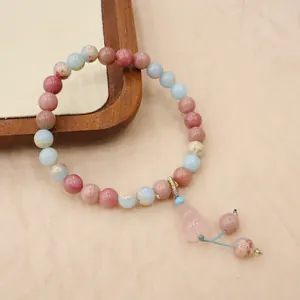 Detail view of a natural pink strawberry quartz bracelet with a crystal gourd pendant.
