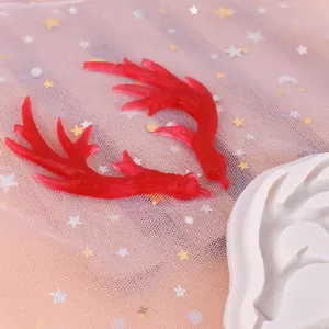 Astas de reno de resina roja junto a un molde de silicona blanca para manualidades DIY.