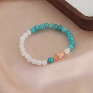 Elegantes Naturkristall-Perlenarmband mit grünem Achat und Sonnenstein auf rosa Seide.