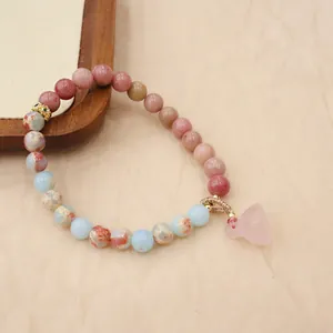 Detailed view of handmade beaded bracelet with strawberry quartz and lotus pod charm
