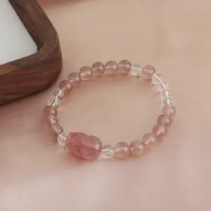 Detailed view of a natural strawberry quartz beaded bracelet with a carved crystal charm