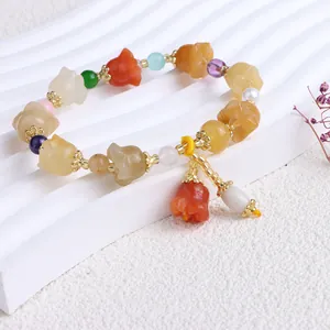 Detailaufnahme eines ethnischen Armbands aus Goldsidenseide-Jade mit bunten Anhängern