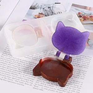 Close-up of cat-shaped DIY resin mold and finished purple glitter mirror case.