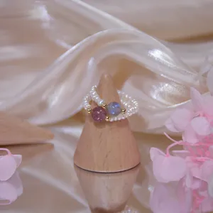 Nahaufnahme eleganter Süßwasserperlenringe mit Erdbeerquarz und Mondstein verziert.