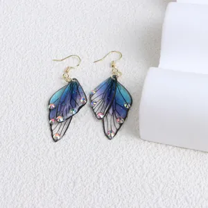 Detailed macro shot of blue-purple butterfly wing earrings with sparkling rhinestones.