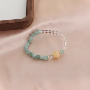 Detailansicht eines Naturkristallarmbands mit grünen Perlen und einer gelben Kürbisperle
