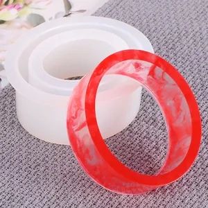Close-up detail of oval C-shaped silicone resin mold with finished red marble bangle