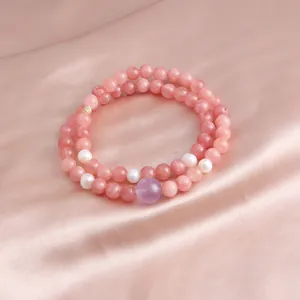 Close-up detail of a double-strand pink stone bracelet with pearls and purple bead.