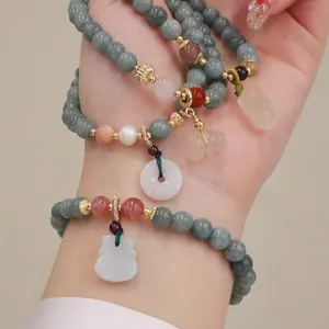 Primo piano di bracciali a strati in giada e quarzo fragola con pendenti fini sul polso.
