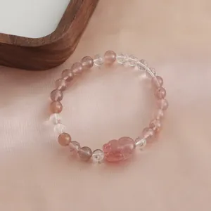 Detailed macro view of a natural strawberry quartz bracelet with lucky carved Pixiu charm.