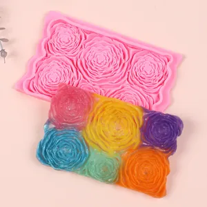 Detailed view of a pink 6-cavity rose silicone mold and colorful fondant samples.