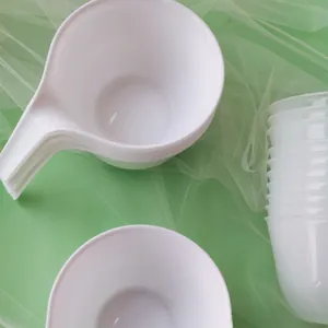 Detailed view of white plastic baking mixing bowls with handles on green background