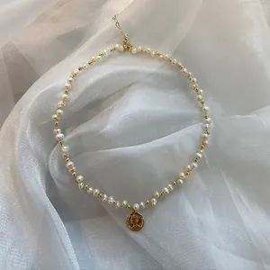 Elegante Detailansicht einer gewebten Natur-Süßwasserperlenkette mit einem Goldmünzenanhänger
