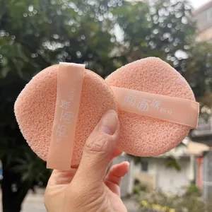 Detailed view of two pink porous makeup sponges featuring elegant satin ribbon straps