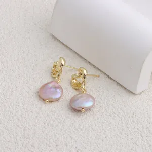Dettaglio di eleganti orecchini barocchi dorati con perle d'acqua dolce rosa naturali.