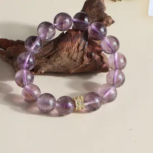 Macro view of 12mm natural purple amethyst beaded bracelet with a decorative gold bead