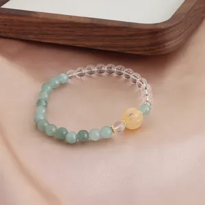 Detailaufnahme eines Armbands mit grünen Achatperlen und einer gelben Kürbisperle
