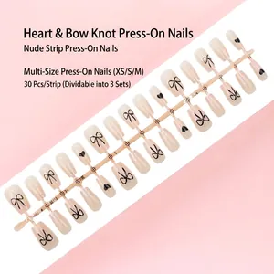 Vue détaillée de 30 faux ongles nude à presser avec motifs de nœuds et cœurs noirs