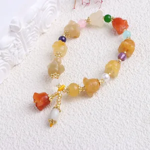 Detailansicht eines bunten Xinjiang Golden Silk Jade Armbands mit geschnitzten Blumenperlen.