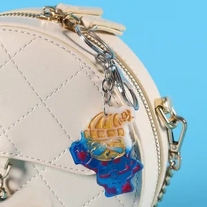 Close-up of a DIY crystal resin Christmas snowman keychain charm on a quilted cream bag