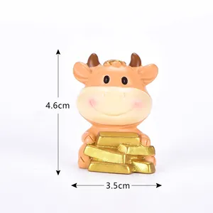 Primo piano di una simpatica figurina di toro dorato in resina con lingotti d'oro e misure.