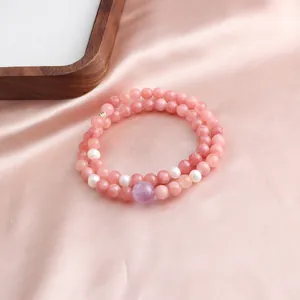 Close-up detail of a pink jade and crystal double-strand bracelet on silk fabric