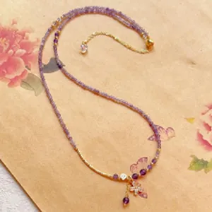 Elegant purple amethyst faceted bead necklace decorated with butterfly and flower charms.