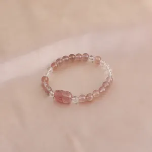 Detailed macro shot of natural strawberry quartz crystal bracelet with a cute cat charm