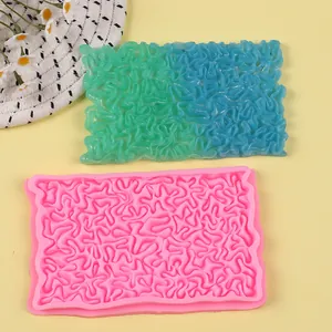 Close-up of pink and teal silicone fondant lace molds with intricate coral wave textures