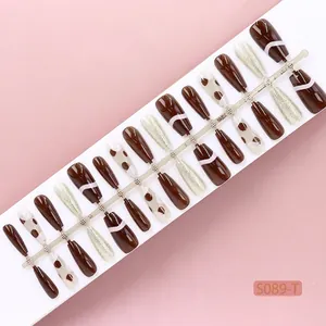 Set of 30 brown and gold glitter press-on nails with polka dot patterns on a display strip