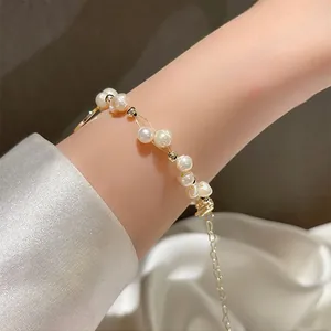 Detailansicht eines eleganten gewebten Natur-Süßwasserperlen-Armbands am Handgelenk