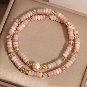 Close-up of double-strand pink opal bracelet featuring a central pearl and gold accents