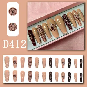 Detailed close-up of almond-shaped press-on nails with luxury brown monogram patterns and gems