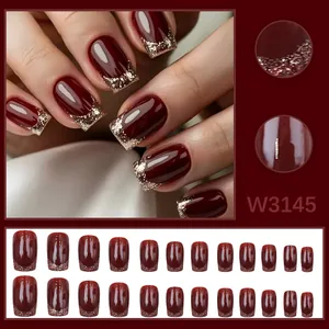 Close-up of elegant cherry red press-on nails with gold glitter tip details