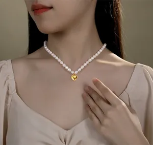 Elegante Natur-Süßwasser-Reisperlenkette mit goldenem Herzanhänger an einem Model